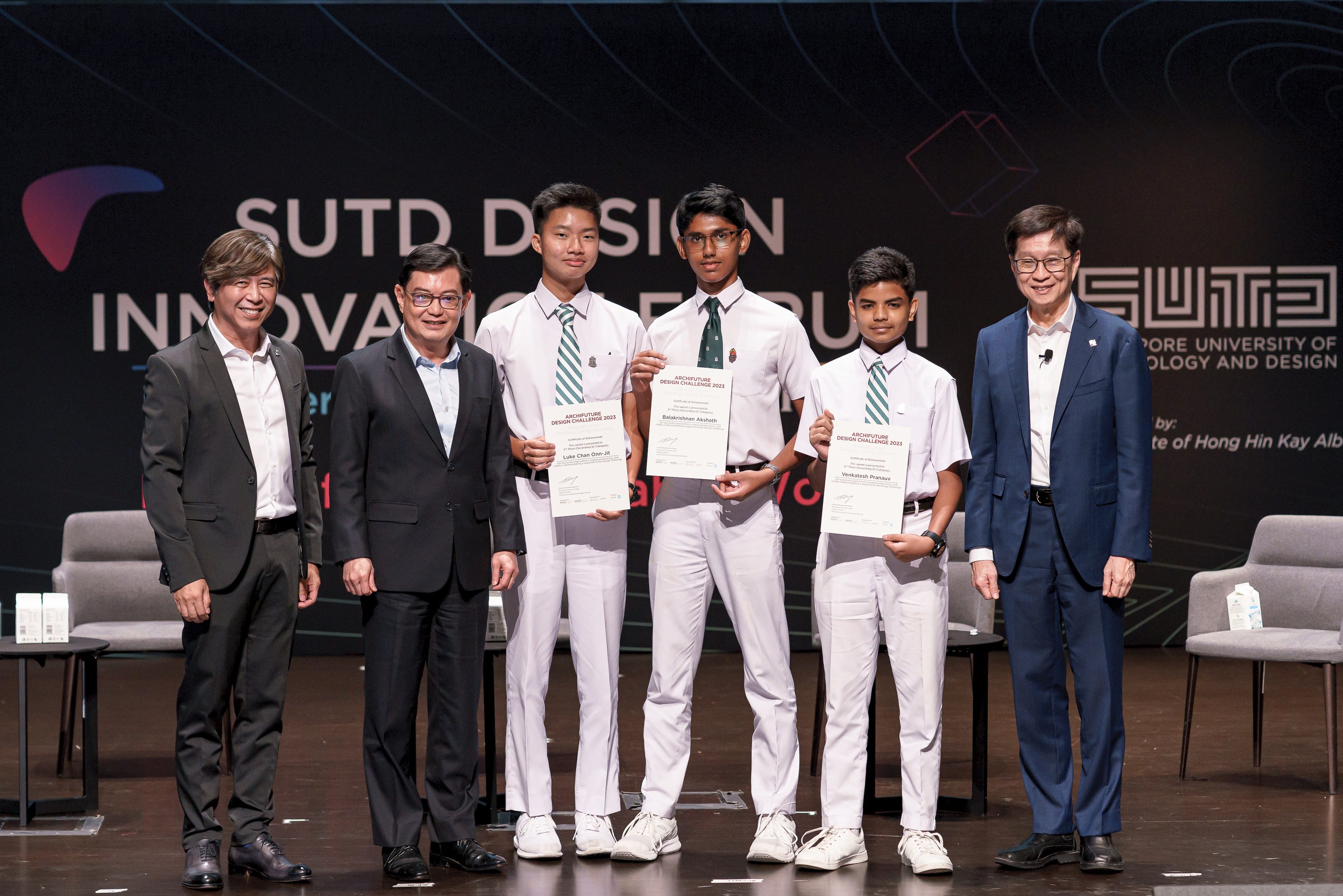 Six people pose on stage at the SUTD Design Innovation Forum, with three students holding certificates.